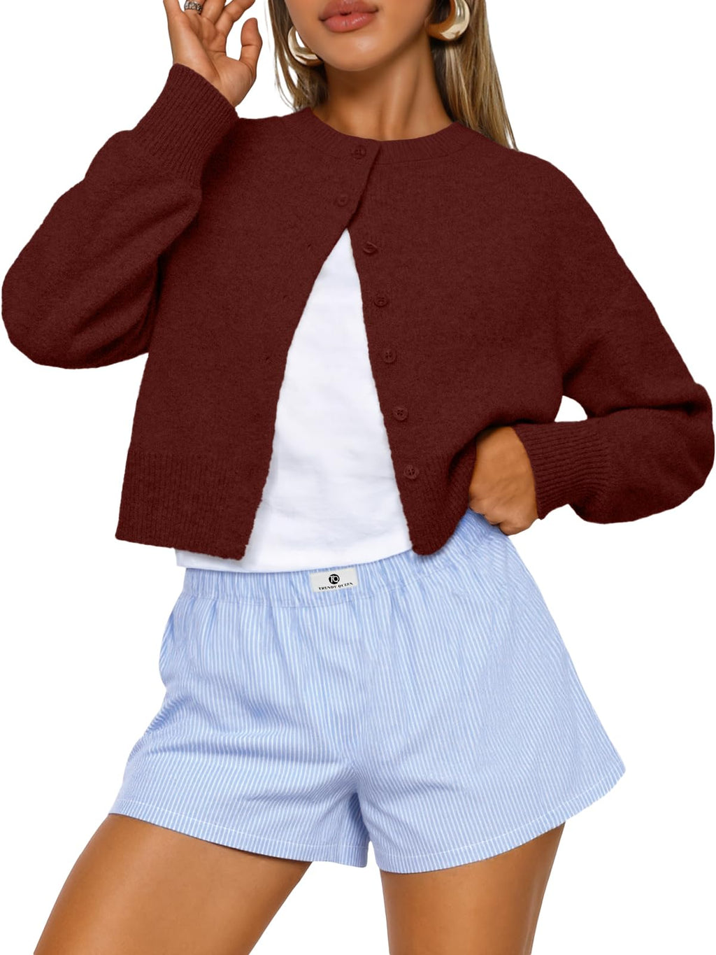 Model wearing the cropped cardigan open over a top, waist-length fit